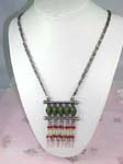 Exotic wholesale fashion jewelry store supplying Tibetan style dangling necklace with green cats eye shaped beads above columns of red, white, and light green beads with feather designed stone hanging below.