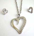 Necklace and earring set sold online at wholesale prices. Heart love shape frame pendant suspended on a snake chain, included a matching a set of studs earrings