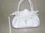 Handbag impoter wholesale company sells womens purses. White imitation leather evening purse with double handle and cinching bows on either side.