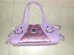 Fashion purse distributed wholesale from China import dealer. Fancy light purple imitation leather handbag with double handles and thin leather strips attached to metal hoop. Shinny fabric with rhinestone design in center